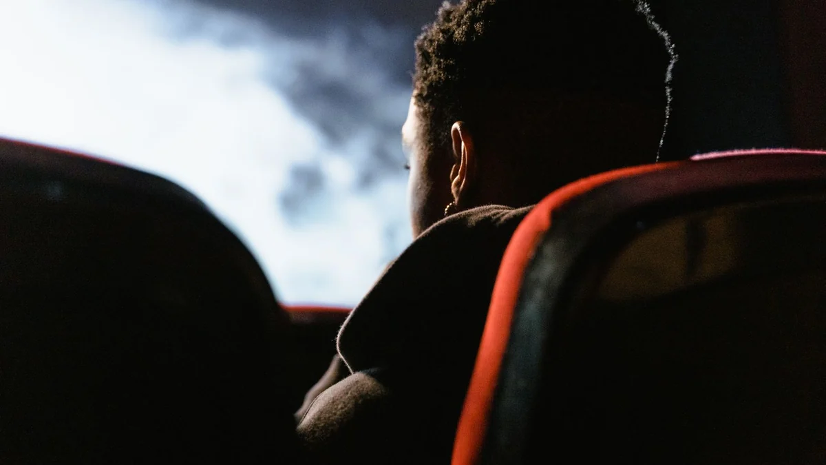 A lone viewer watching a large screen in a darkened auditorium
