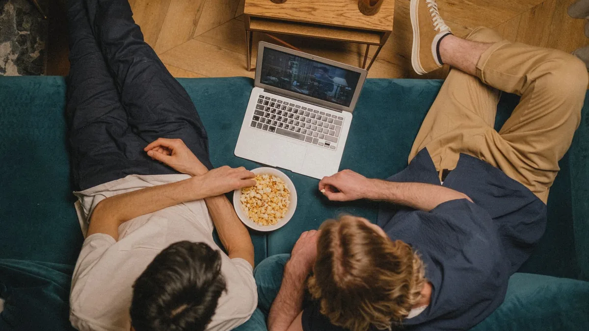 Friends watching a film together on a laptop with popcorn