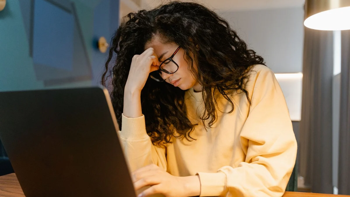 A person looking tired and frustrated at a laptop screen