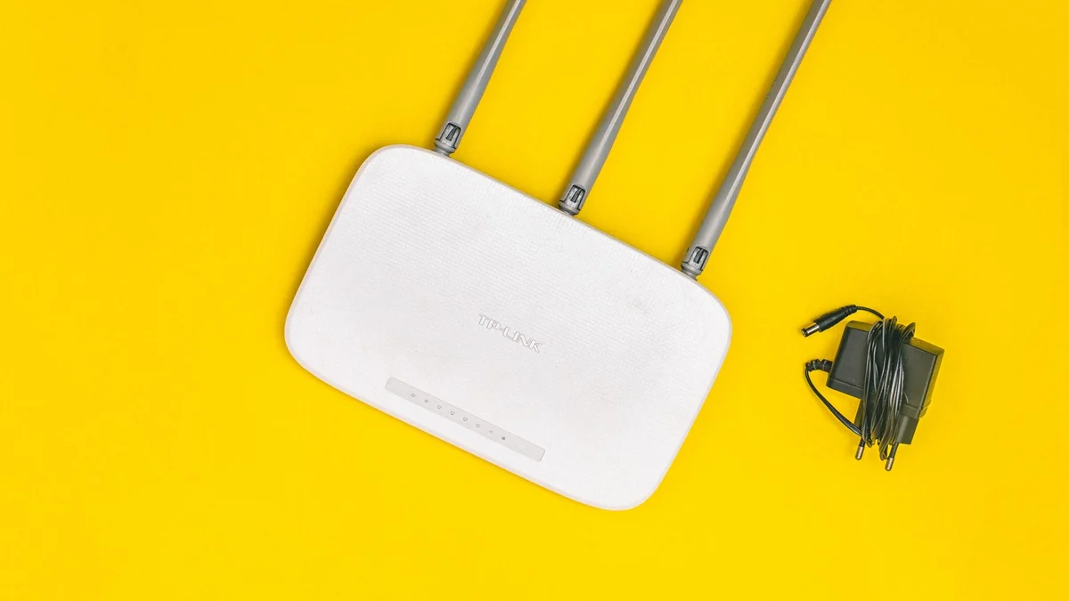 A wireless router with three antennas against a plain background