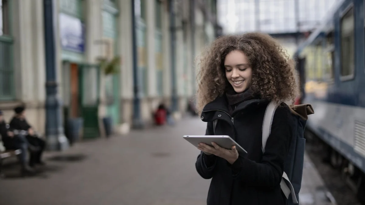 A woman using a tablet while waiting on a railway platform
