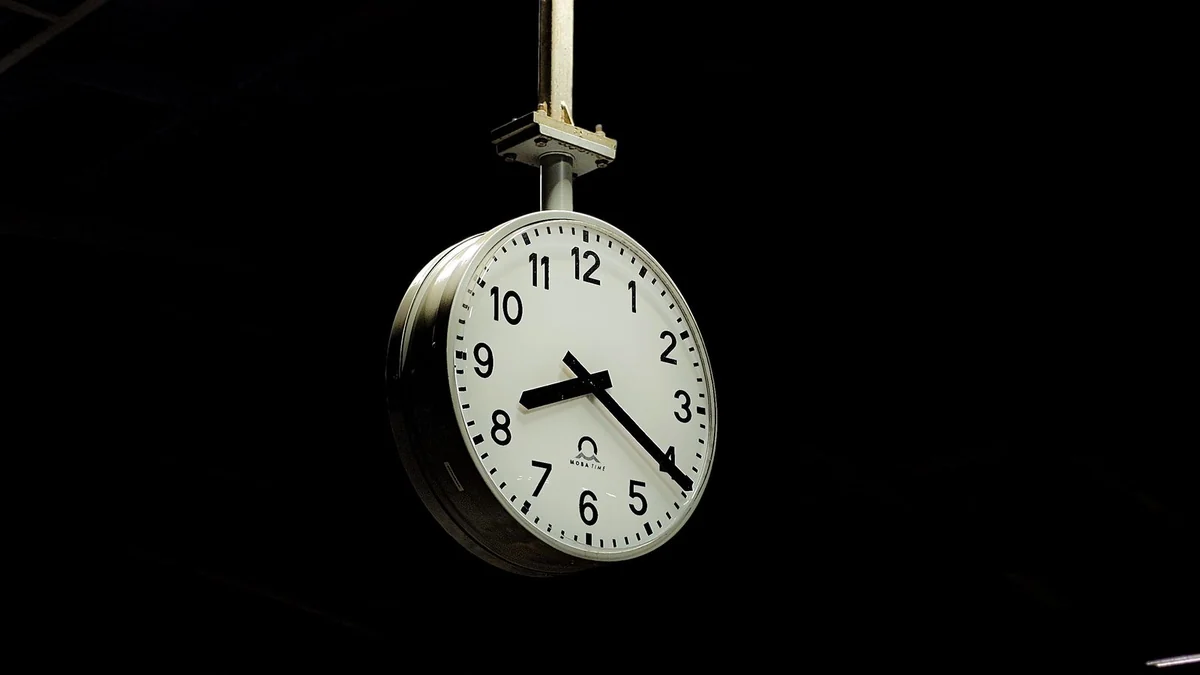 A station clock hanging in a dark railway hall