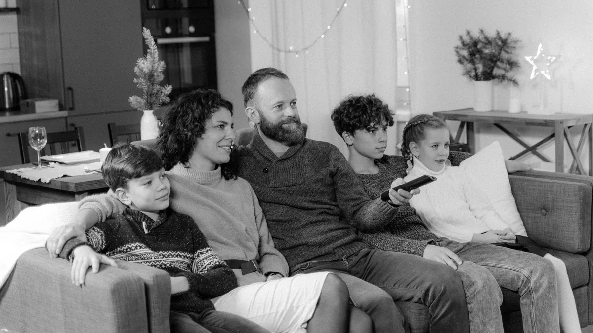 A group of people sharing a sofa on a cosy evening at home