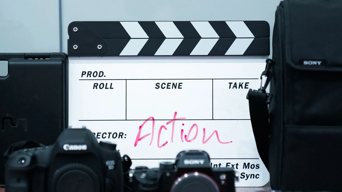 A clapperboard and cameras arranged on a desk