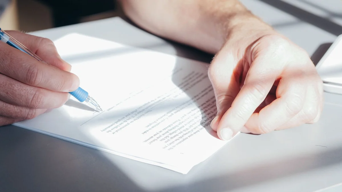 Two people signing a contract at a desk