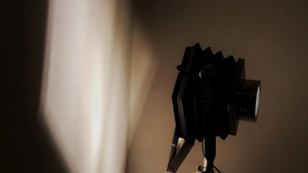 A classic film camera on a tripod casting shadows in a studio