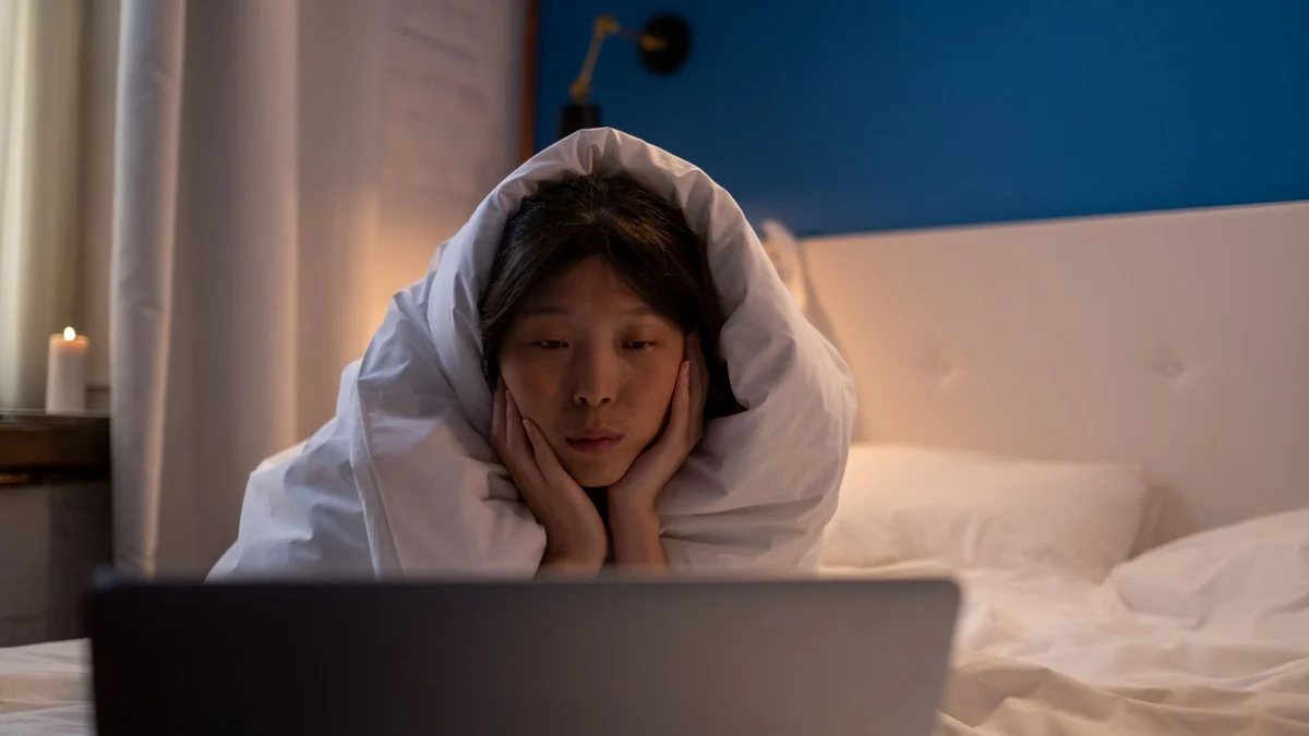A person wrapped in a blanket watching a laptop screen