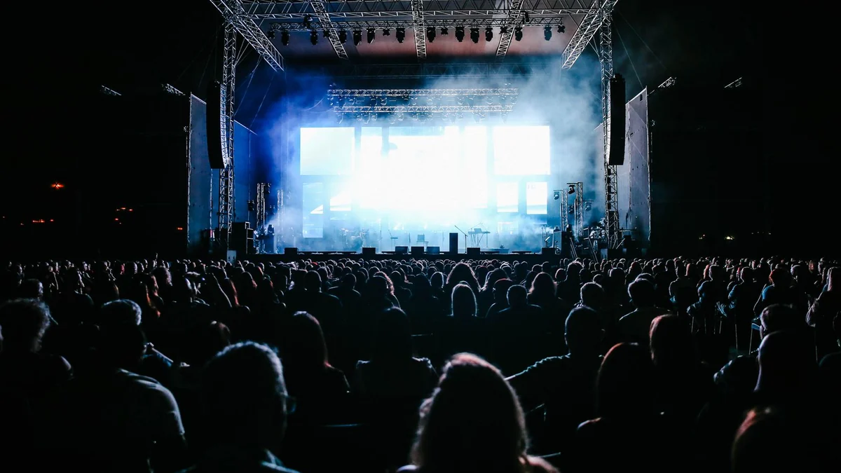 A large crowd gathered at an outdoor event under coloured lights