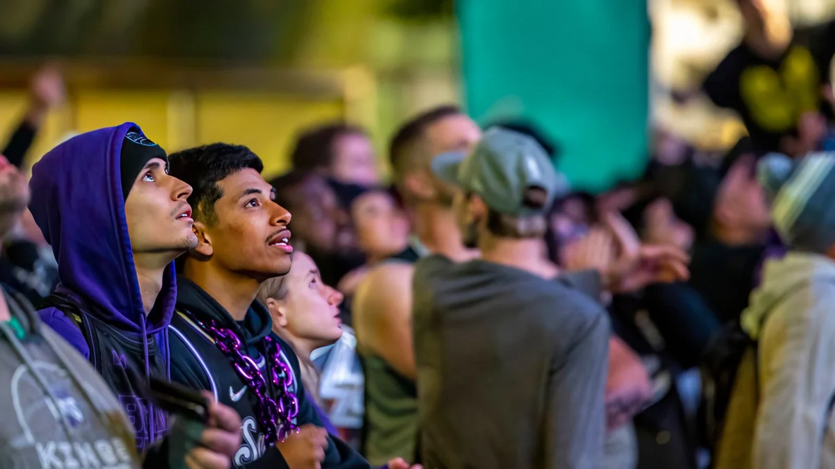 A crowd watching an evening event under lights
