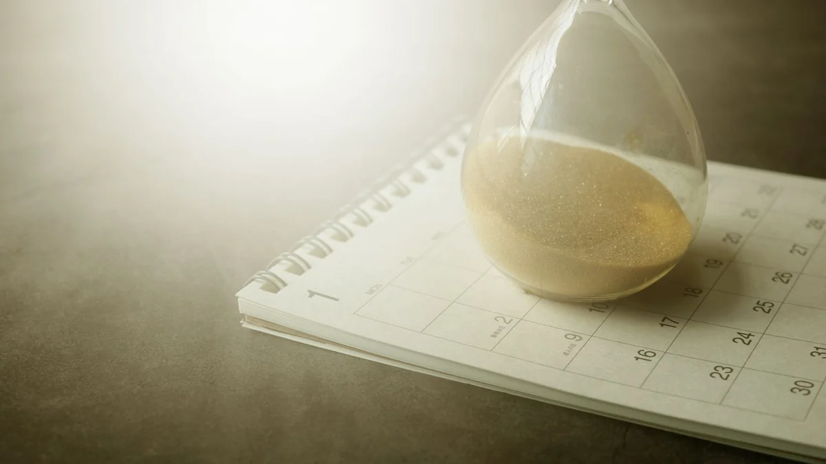 An hourglass resting on an open calendar