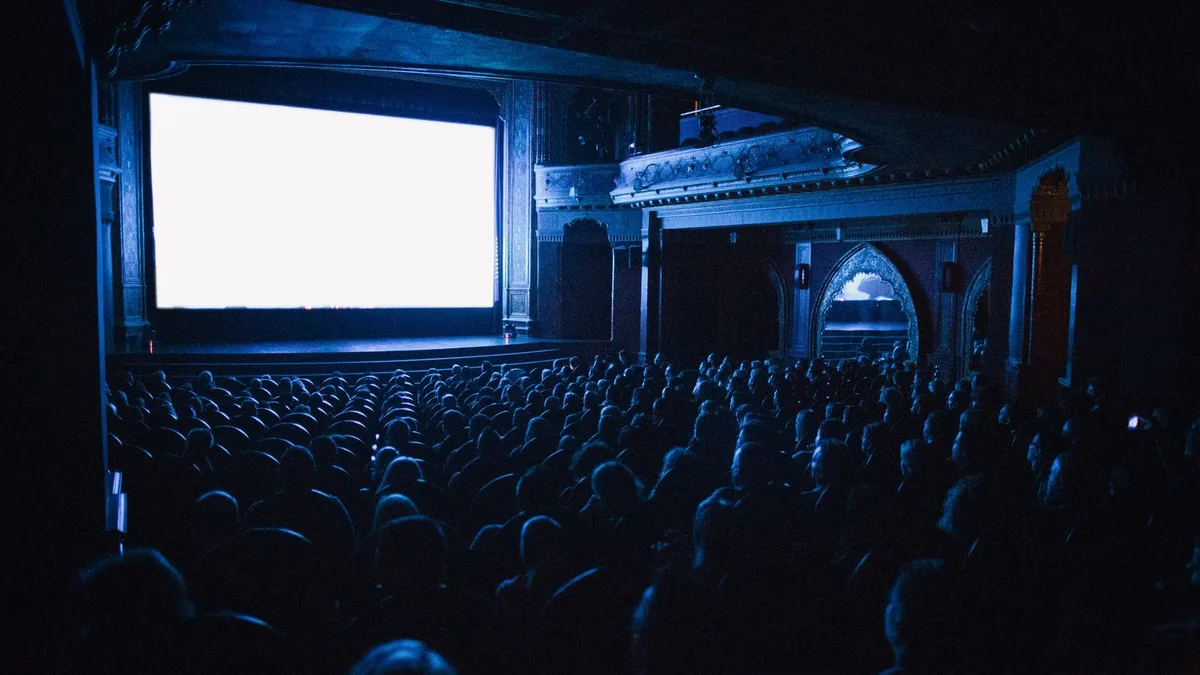 An audience watching a film in a full cinema at night