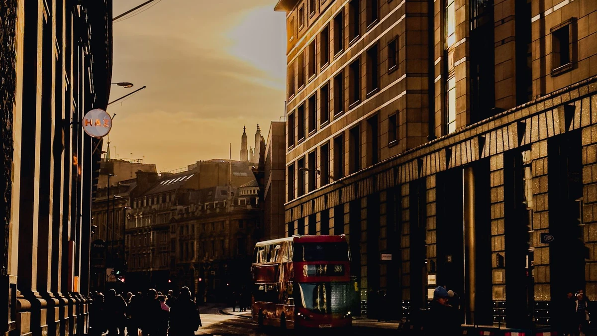A red double-decker bus on a London street at golden hour