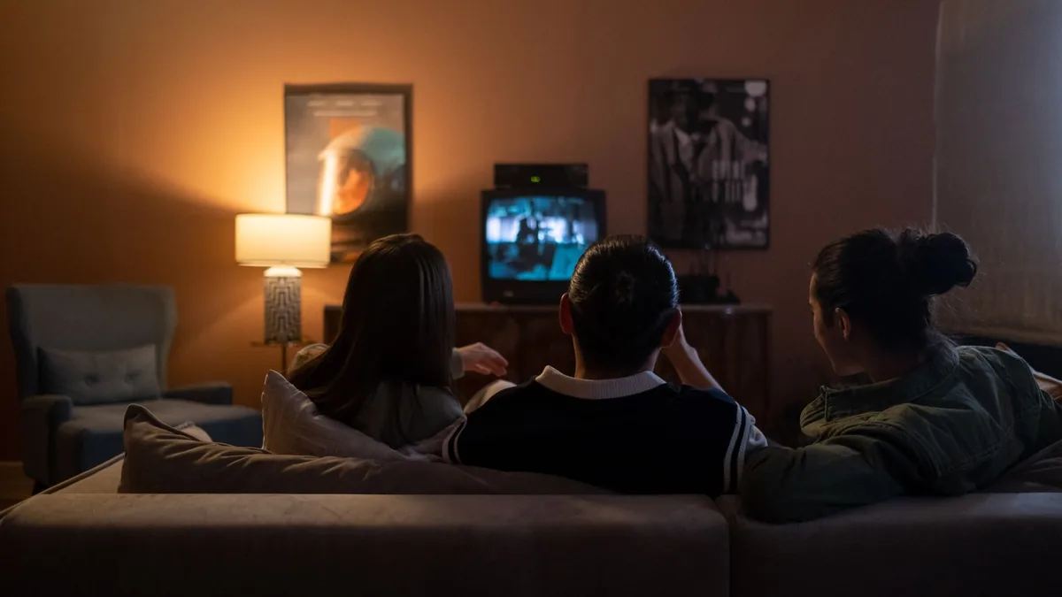Three people watching television together in a warmly lit living room