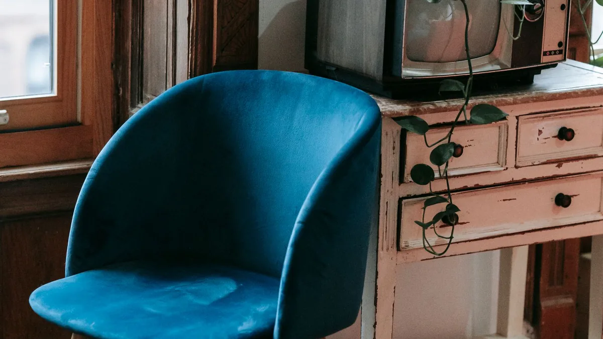 An armchair beside a cabinet holding an older television