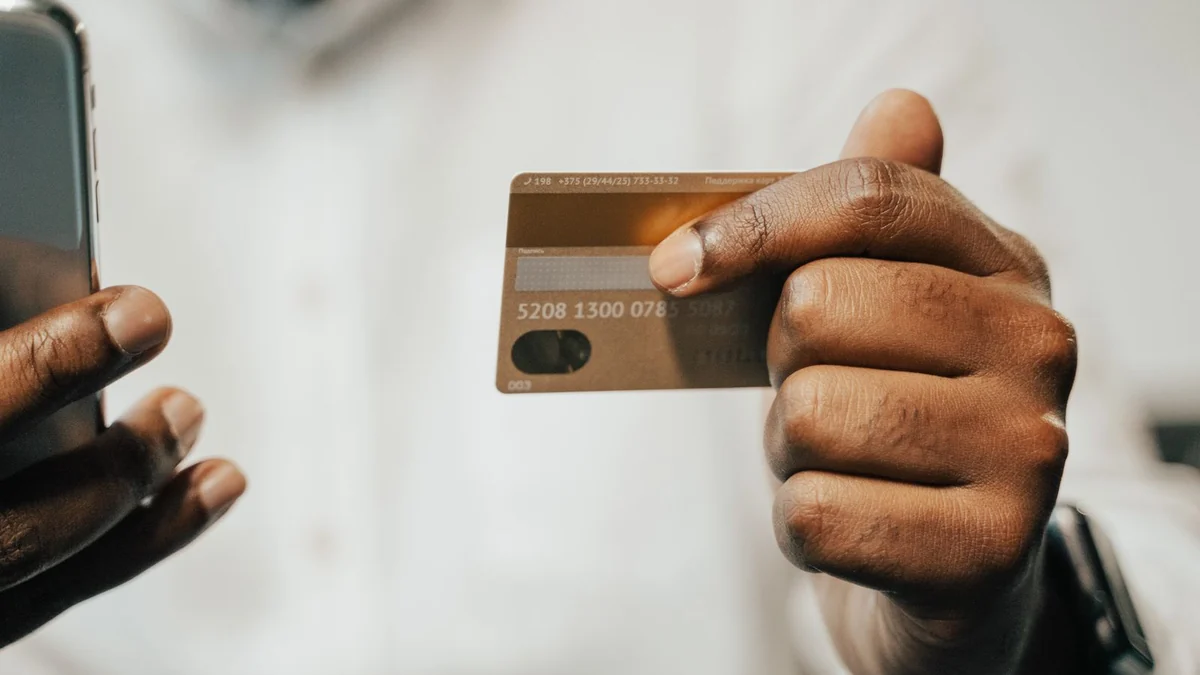 A person holding a payment card and a phone