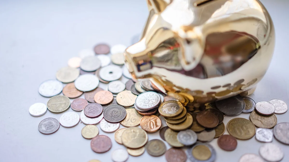 A golden piggy bank surrounded by assorted coins