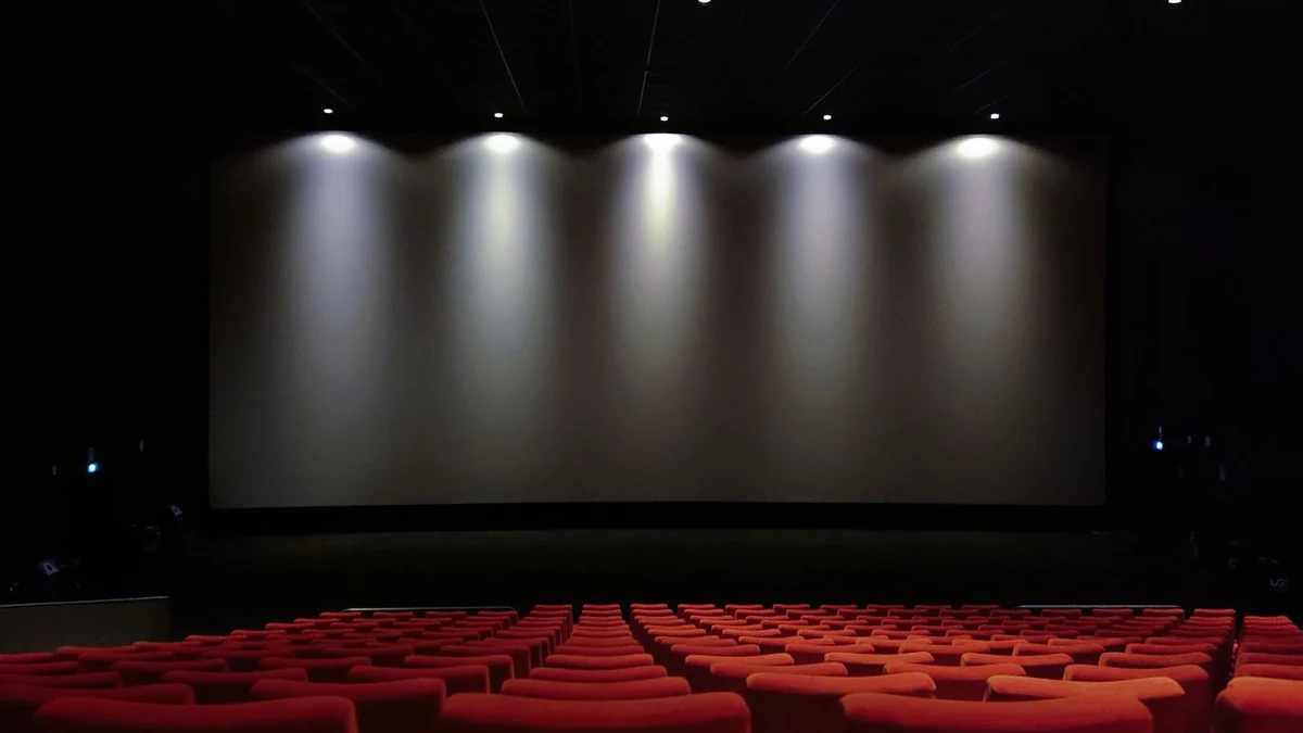 Rows of red cinema seats facing an illuminated screen