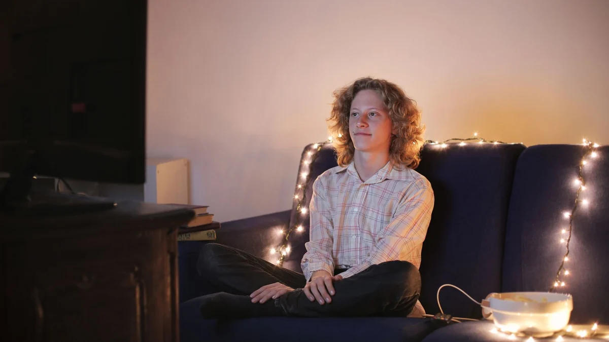A man relaxing on a sofa watching television