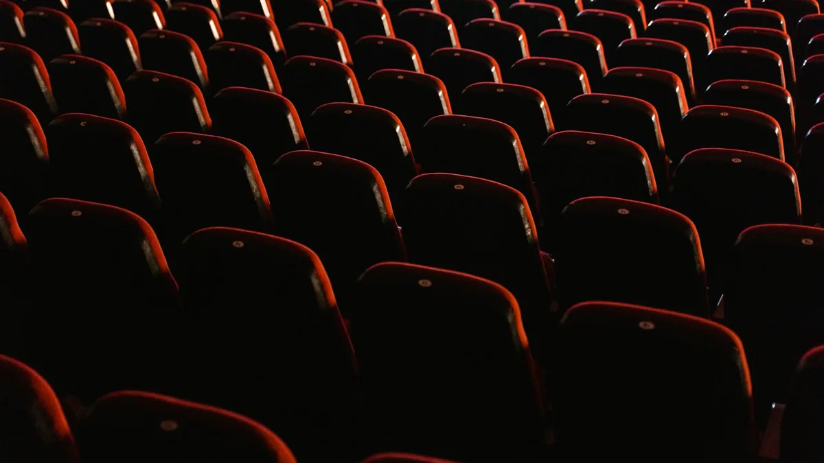 Empty red cinema seats lit softly in a quiet auditorium