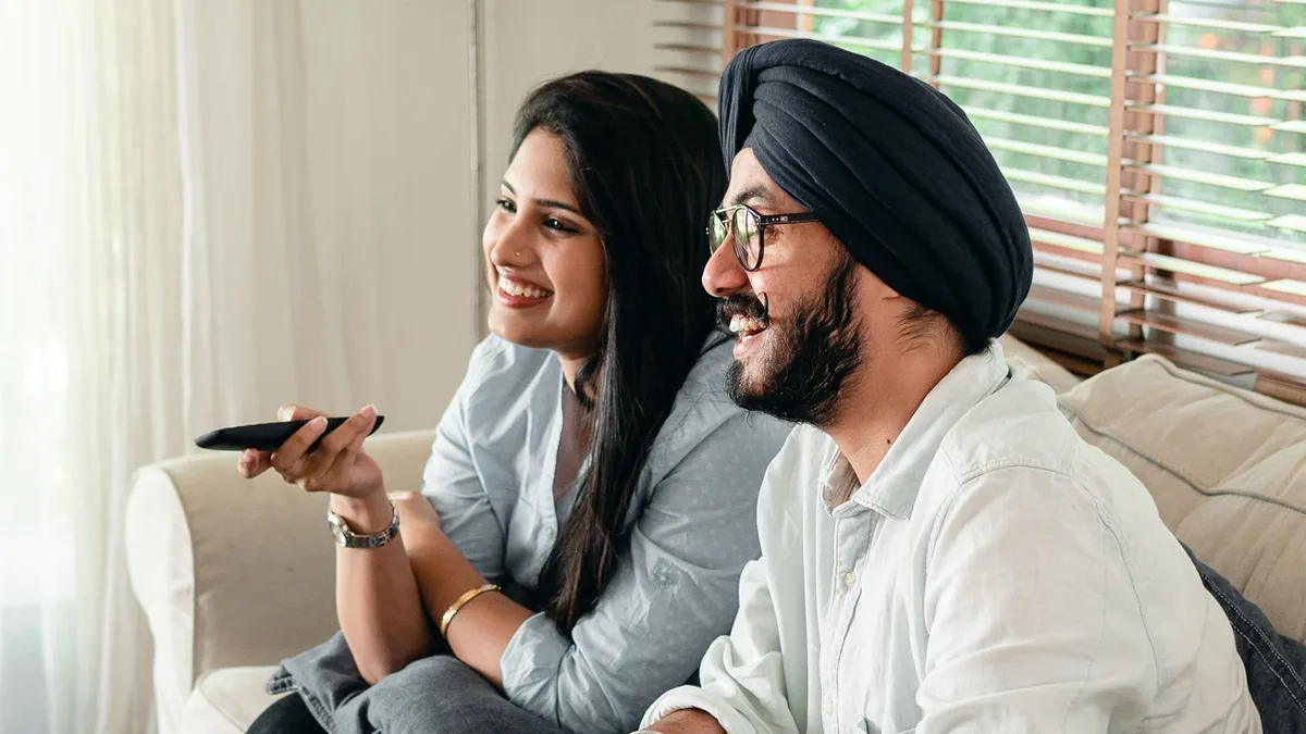A couple sitting on a sofa watching television together