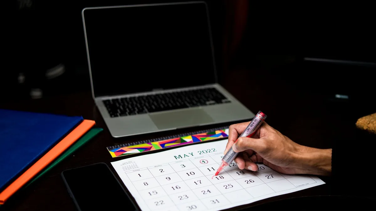 A person marking a date on a wall calendar