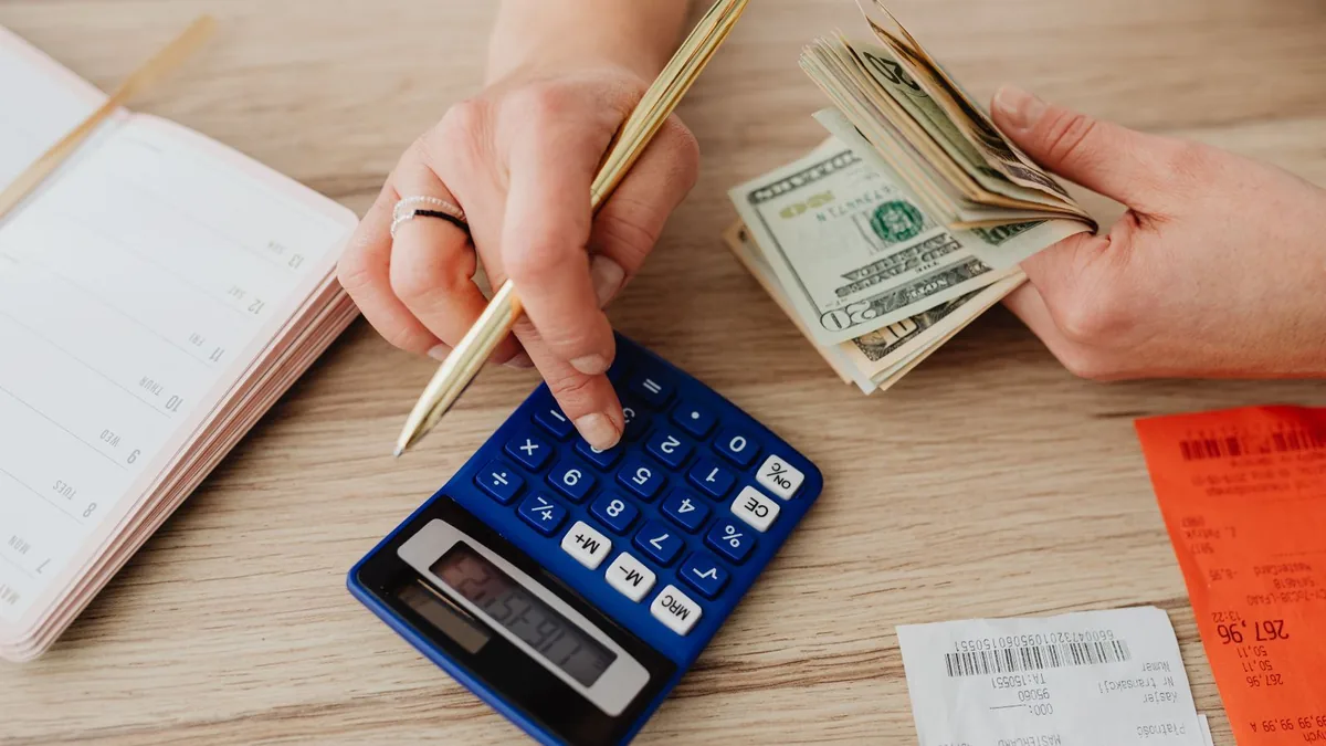 A person working out monthly costs with a calculator and receipts