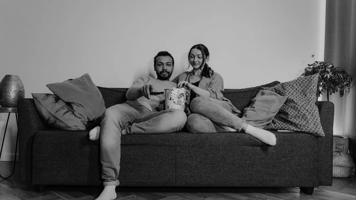 A couple watching television together with a bucket of popcorn