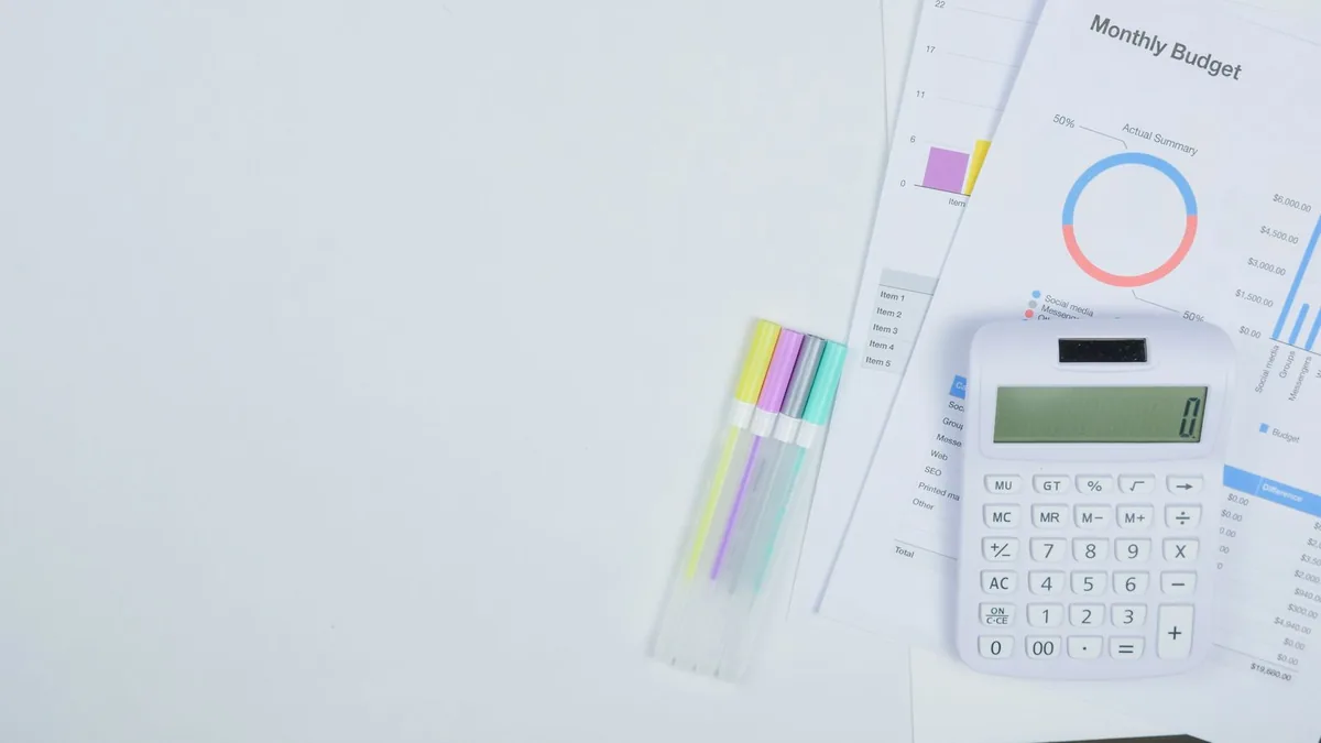 A notepad and calculator laid out for monthly budget planning