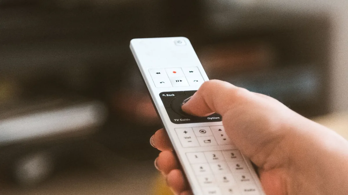 A hand using a television remote control to change channel