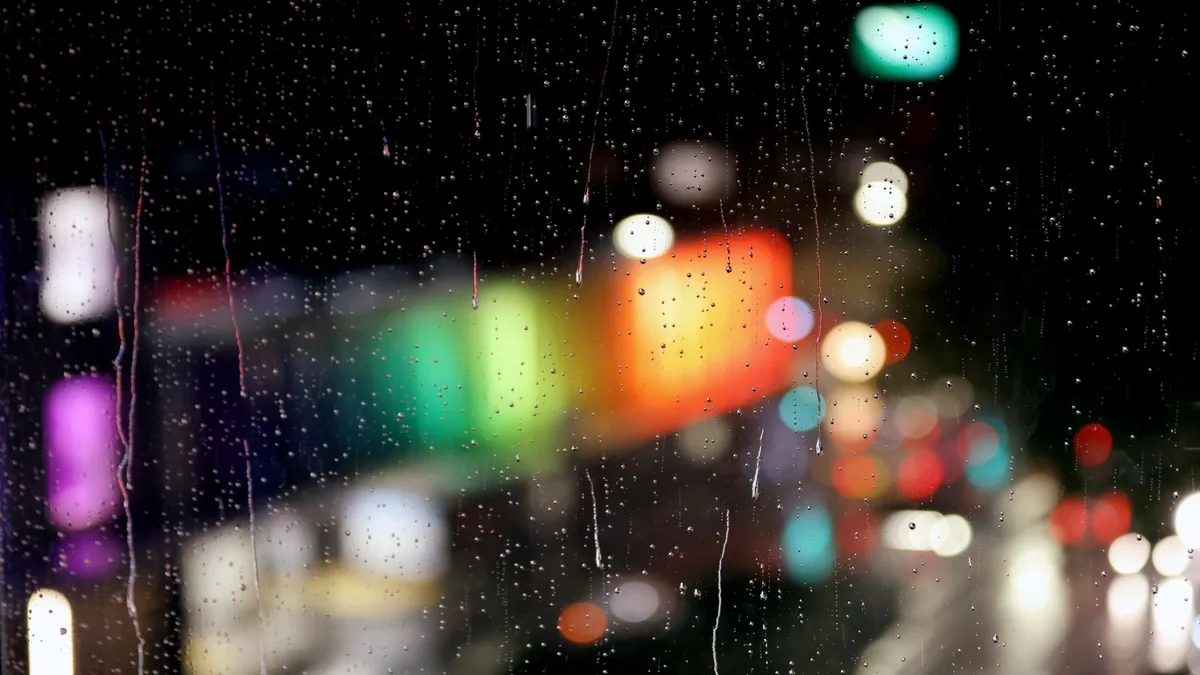Raindrops on a window with blurred city lights behind